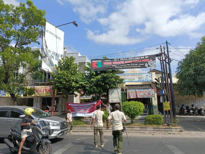 petugas satpol PP Kota Solo tengah mencopoti sejumlah spanduk people power